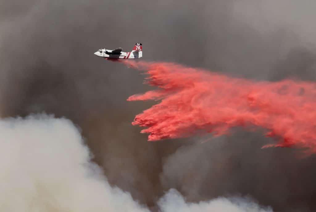 plane dumping water on fire during aerial firefighting mission