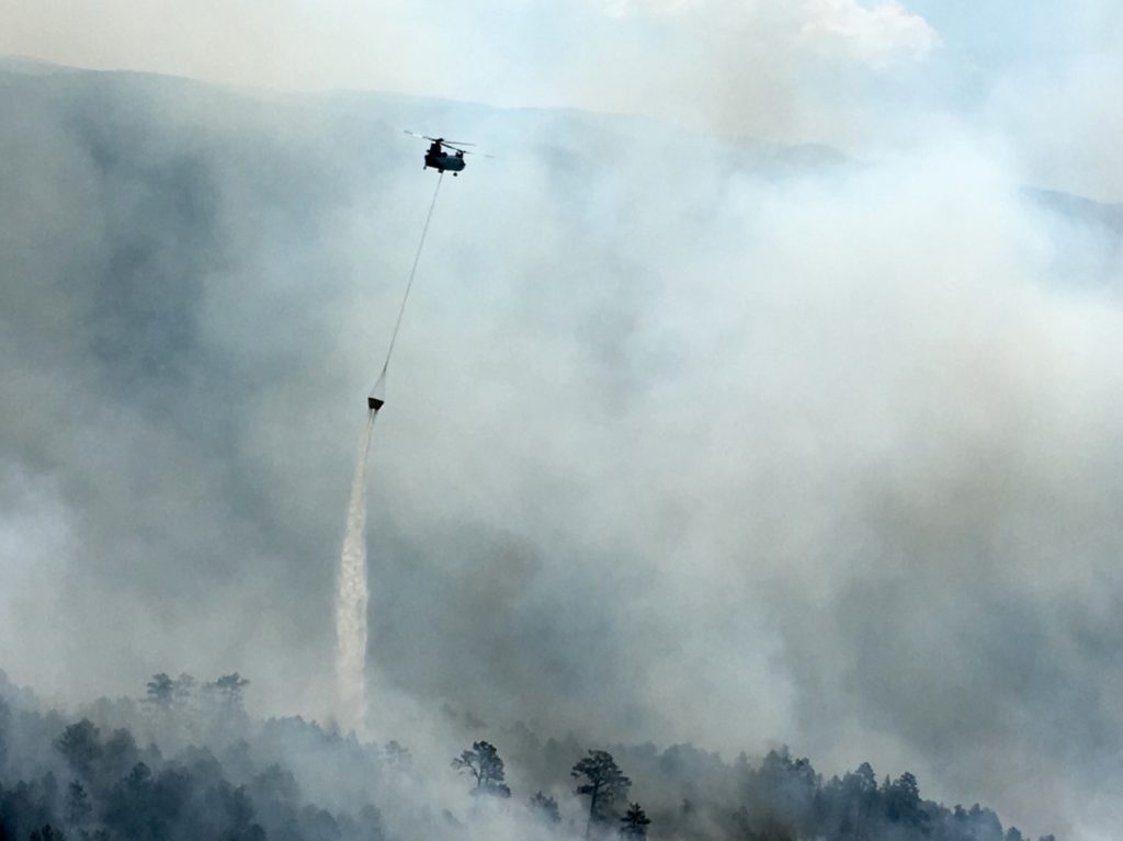 chinook helicopter fire fighting dumping water bucket over wildfire